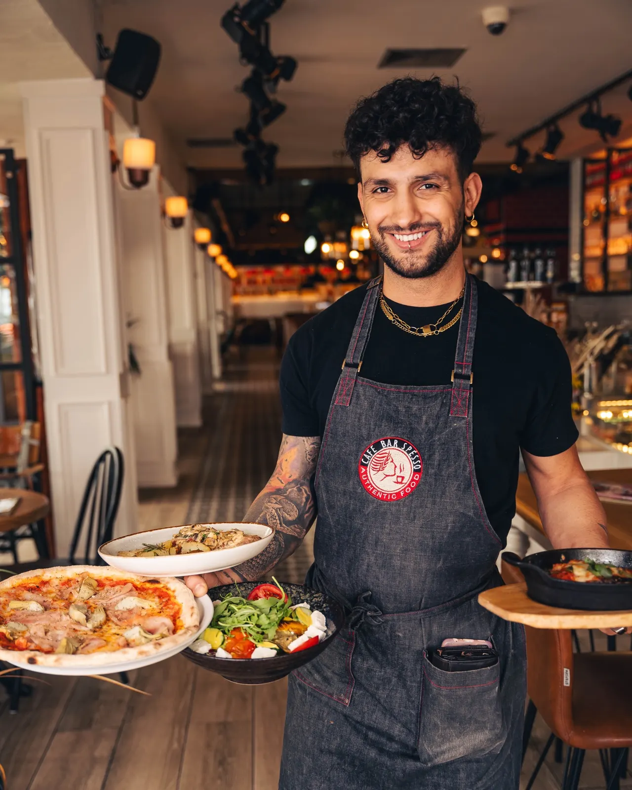 Personalaufnahme im Restaurant: Kellner von Spesso serviert Pizza